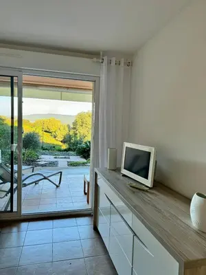a living room with a tv and a sliding glass door at Appart résidence avec piscine in Propriano
