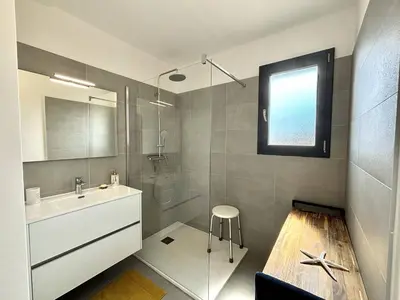a bathroom with a sink and a shower and a stool at Appartement Cargèse Théâtre de Verdure in Cargèse