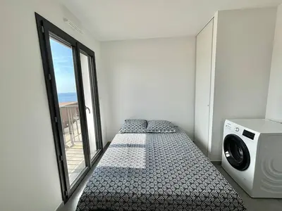a bedroom with a bed and a large window at Appartement Cargèse Théâtre de Verdure in Cargèse