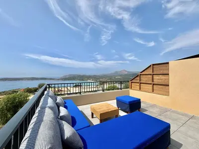 a balcony with blue furniture and a view of the ocean at Appartement Cargèse Théâtre de Verdure in Cargèse
