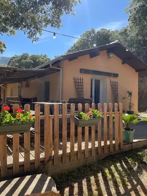 a wooden fence in front of a house with flowers at Jolie maison familiale au cœur des vignes in Sartène