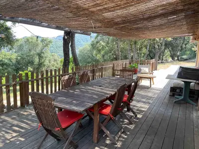 a wooden table and chairs on a wooden deck at Jolie maison familiale au cœur des vignes in Sartène