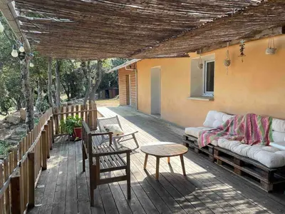 a porch with a couch and a table and chairs at Jolie maison familiale au cœur des vignes in Sartène