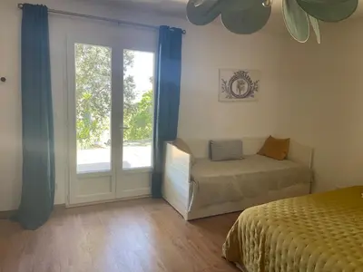 a bedroom with a bed and a sliding glass door at Jolie maison familiale au cœur des vignes in Sartène