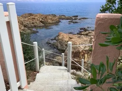 a stairway leading down to a beach with the ocean at Magique Creek, piscine naturelle dans les rochers in Zonza