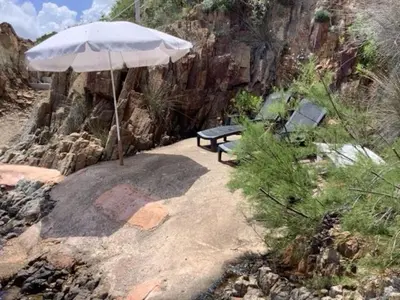 a bench with an umbrella on a rocky hill at Magique Creek, piscine naturelle dans les rochers in Zonza