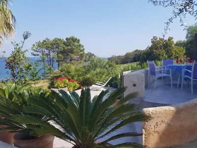 a patio with a table and chairs overlooking the water at Magique Creek, piscine naturelle dans les rochers in Zonza