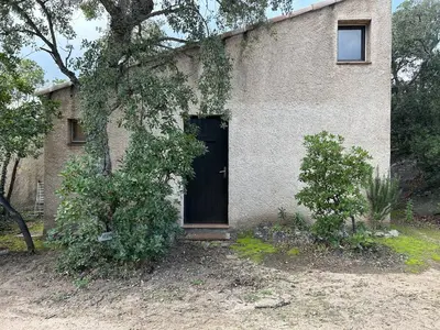 an old brick house with a black door at Mini-villa à 1 minute de la plage de Santa Giulia in Porto-Vecchio