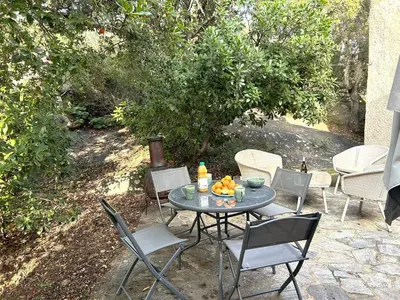 a patio with a table with chairs and fruit on it at Mini-villa à 1 minute de la plage de Santa Giulia in Porto-Vecchio