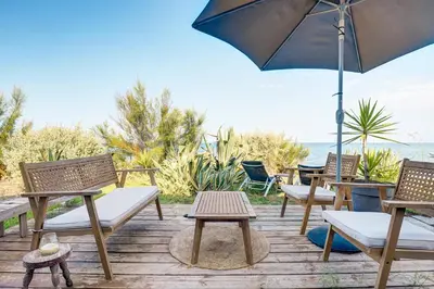 a group of chairs and tables with an umbrella at A Stalla - Maison pieds dans l'eau à Lucciana in Lucciana