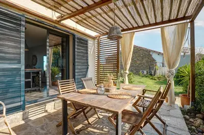 a wooden table and chairs on a patio at A Stalla - Maison pieds dans l'eau à Lucciana in Lucciana