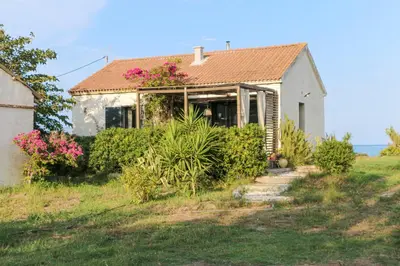 a small white house with pink flowers on it at A Stalla - Maison pieds dans l'eau à Lucciana in Lucciana