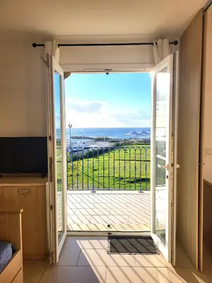 a room with a door open to a balcony with a view at 4-6 couchages vue mer et port de Solenzara Corse in Sari Solenzara