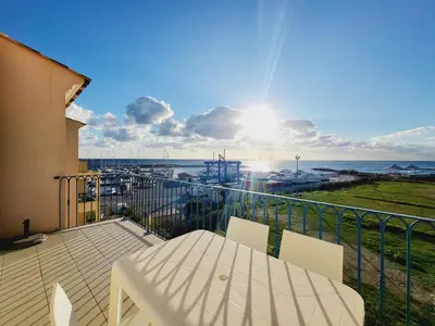 a balcony with a table and a view of the ocean at 4-6 couchages vue mer et port de Solenzara Corse in Sari Solenzara
