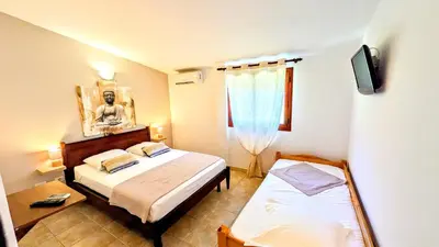 a small room with two beds and a tv at Auberge de Cannedda in Sari Solenzara
