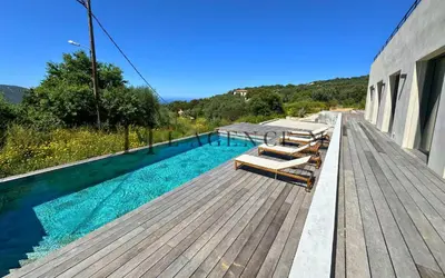 a swimming pool on a wooden deck next to a building at Villa Giuliana Paisible & spacieuse AREGNO in Aregno