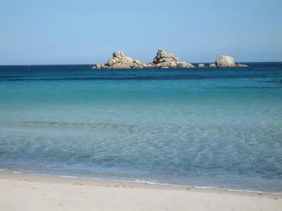 a beach with a group of rocks in the water at BLU DI MARE Palombaggia in Porto-Vecchio