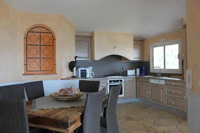 a kitchen with a table and chairs and a kitchen with a stove at BLU DI MARE Palombaggia in Porto-Vecchio