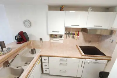 a kitchen with white cabinets and a sink at Bright apartment 3 minutes from the beach in Ajaccio