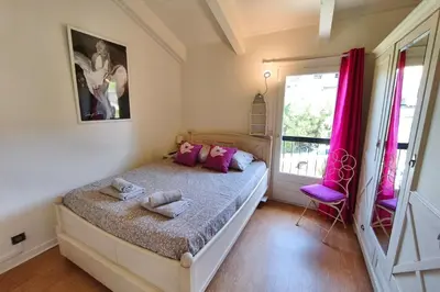 a bedroom with a bed with pink pillows on it at Bright apartment 3 minutes from the beach in Ajaccio