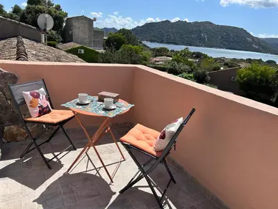 a table and chairs on a balcony with a view of the water at Mini villa en duplex vue mer à 500 m de la plage de Santa Giulia in Porto-Vecchio