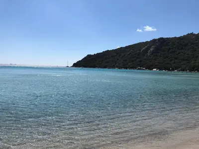 a large body of water with a mountain in the background at Mini villa en duplex vue mer à 500 m de la plage de Santa Giulia in Porto-Vecchio