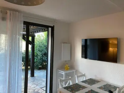 a dining room with a table and a television on the wall at Mini villa en duplex vue mer à 500 m de la plage de Santa Giulia in Porto-Vecchio