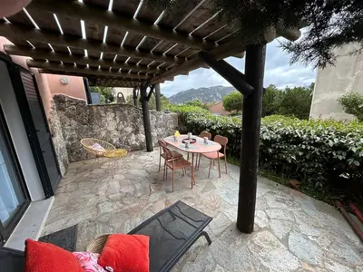 a patio with a table and chairs under a pergola at Mini villa en duplex vue mer à 500 m de la plage de Santa Giulia in Porto-Vecchio