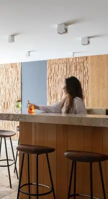 a woman sitting at a counter with three bar stools at Dominique Colonna in Corte