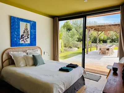 a bedroom with a bed and a sliding glass door at Villa Dina - Douceur et calme in Bonifacio