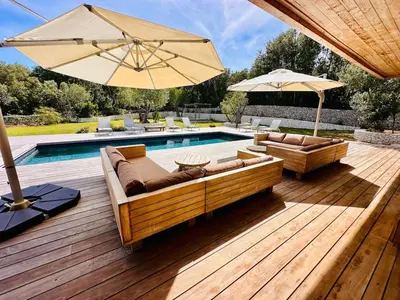 a pool deck with a couch and an umbrella at Villa Dina - Douceur et calme in Bonifacio
