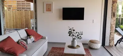 a living room with a couch and a tv on a wall at Casa PETRA et FIORI, une bergerie en pierres authentiques toute équipée - 4 personnes in Pietrosella