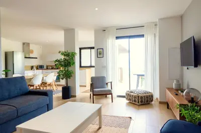 a living room with a blue couch and a kitchen at Villa Maquis, Vue mer, élégante maison au calme, 80m2, 4 personnes in Pietrosella