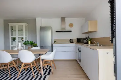 a kitchen with white cabinets and a table and chairs at Villa Maquis, Vue mer, élégante maison au calme, 80m2, 4 personnes in Pietrosella