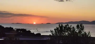 a sunset over the ocean with people in the water at Villa Maquis, Vue mer, élégante maison au calme, 80m2, 4 personnes in Pietrosella