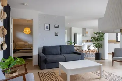 a living room with a blue couch and a kitchen at Villa Maquis, Vue mer, élégante maison au calme, 80m2, 4 personnes in Pietrosella