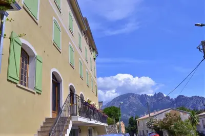 a building with a balcony and mountains in the background at Auberge - Hotel U Paradisu in Vico
