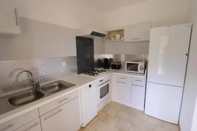 a white kitchen with a sink and a refrigerator at Résidence Capizzolu in Cargèse
