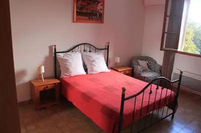 a bedroom with a bed with a red blanket and a chair at Villa climatisée, superbe vue mer in Ventiseri