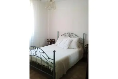 a bedroom with a bed with white sheets and a chandelier at Villa climatisée, superbe vue mer in Ventiseri