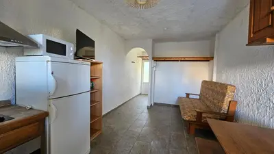 a kitchen with a refrigerator and a chair and a table at LA PALGE Le Centuri in Linguizzetta