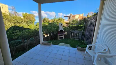 a porch with a chair and a yard with a lighthouse at LA PALGE Le Centuri in Linguizzetta