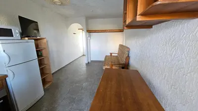 a kitchen with a wooden table and a refrigerator at LA PALGE Le Centuri in Linguizzetta