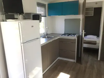 a small kitchen with a refrigerator and a sink at Camping Milella in Propriano