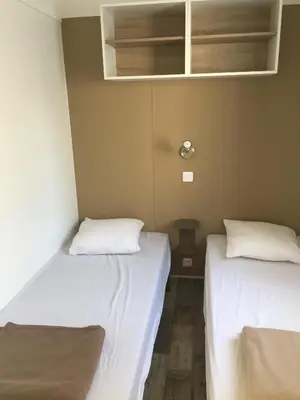 two beds in a room with white sheets at Camping Milella in Propriano