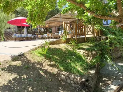 a house with a red umbrella and a table at Camping Milella in Propriano
