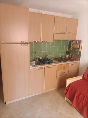 a kitchen with wooden cabinets and a sink at Les jardins de la mer marine de Bravone in Linguizzetta
