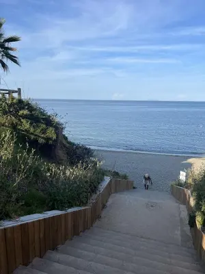a person walking down the stairs to the beach at Les jardins de la mer marine de Bravone in Linguizzetta