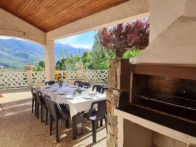 a dining table and chairs on a patio with a fireplace at Villa avec vue panoramique sur les montagnes in Corscia