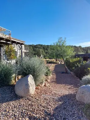 a garden with rocks and trees and a building at Haut de Villa - Corsica in Lecci